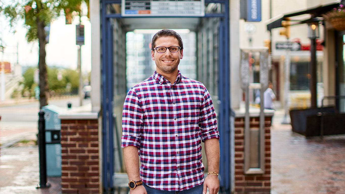 A man wearing glasses exaggerates his point to the camera while smiling